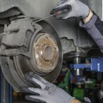 Mechanic measuring a car brake rotor with a caliper in a garage