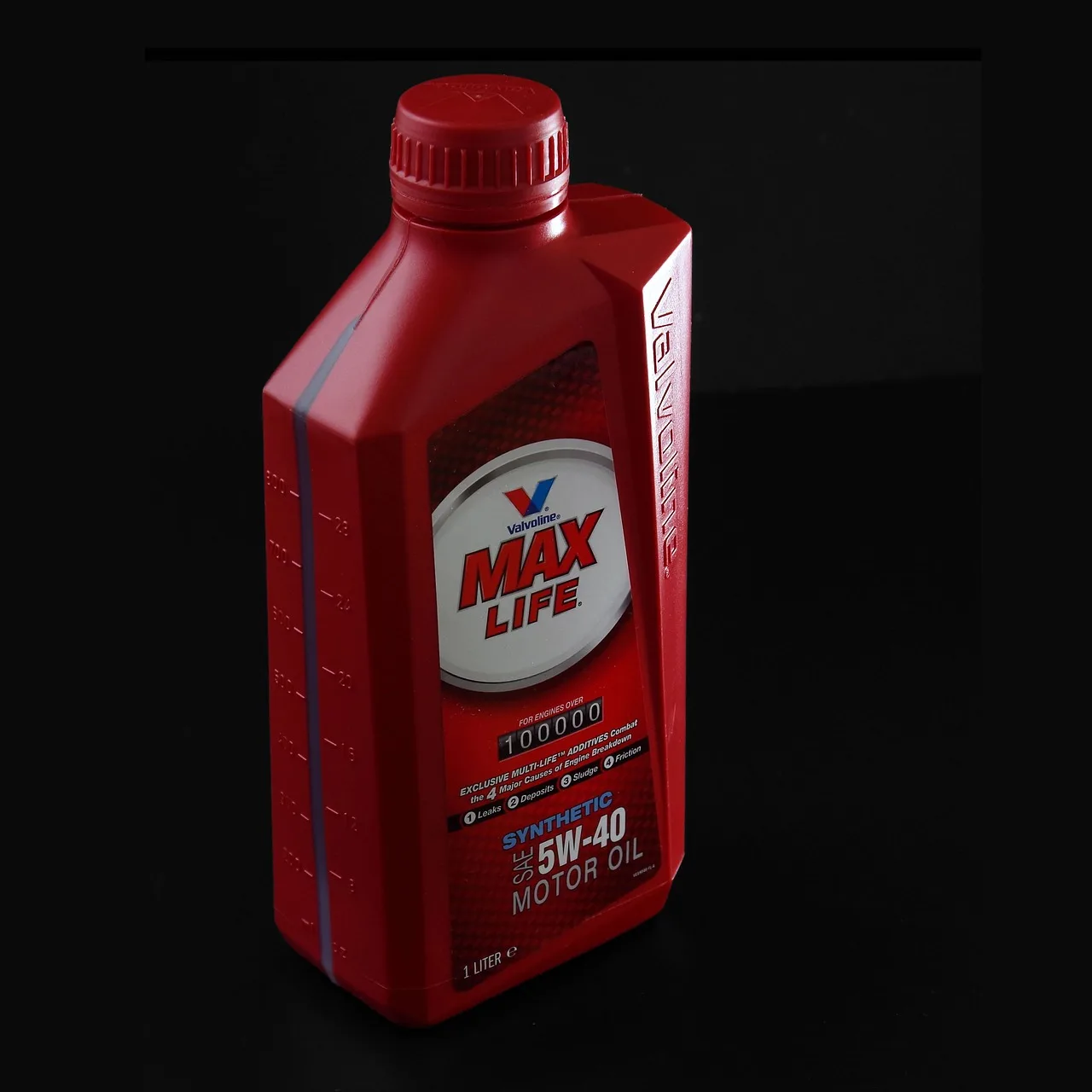 Mechanic comparing synthetic and conventional engine oil bottles beside an open car hood
